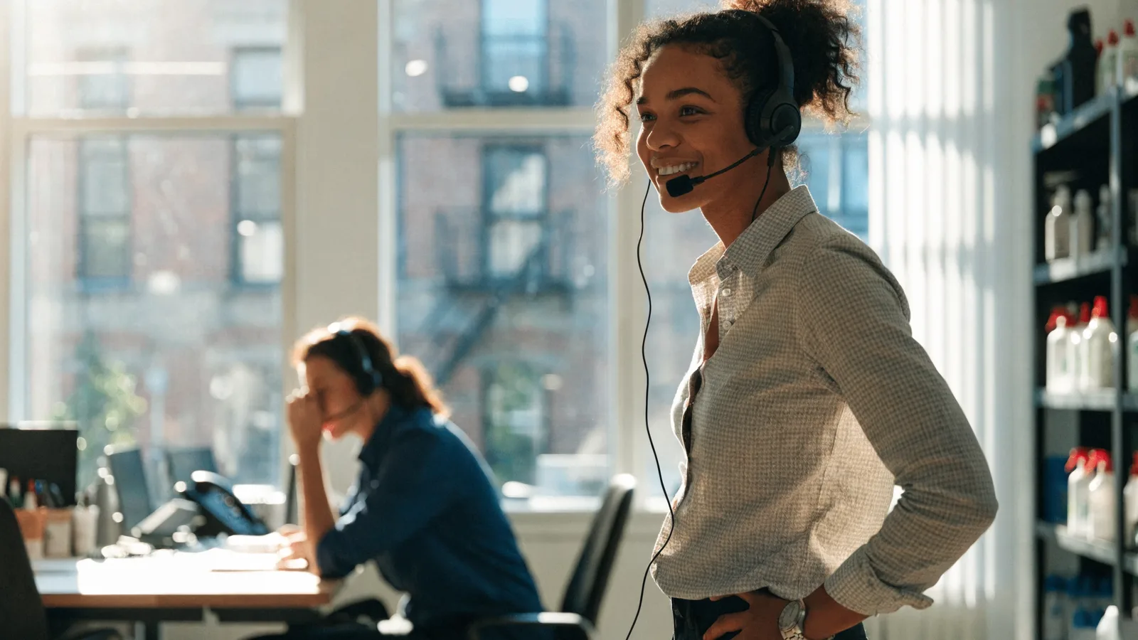 Photo of a headset-wearing pest control office rep handling calls while a colleague works nearby, illustrating an AI CRM that acts on customer data