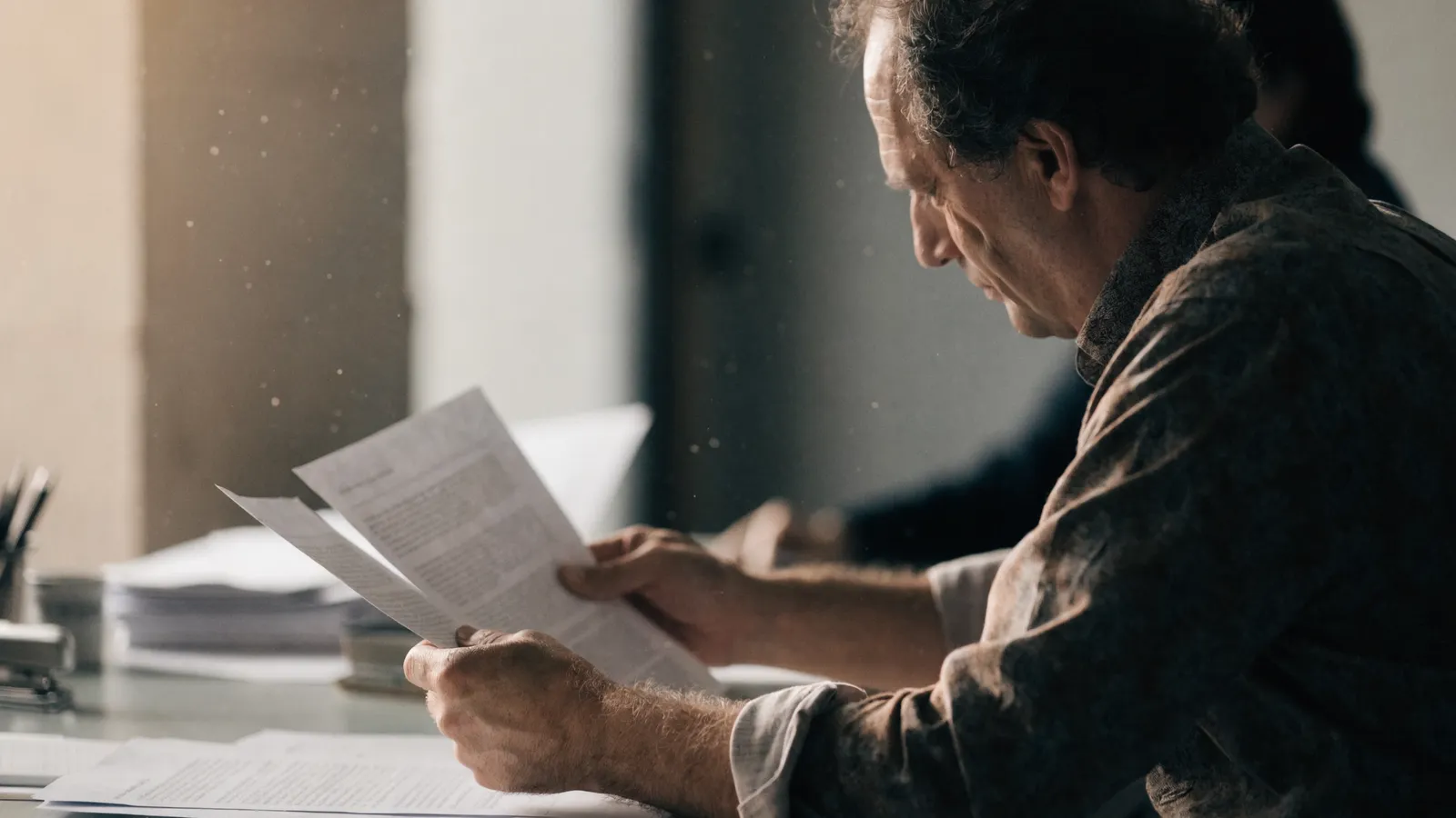 Photo of a pest control operator at a desk reading printed reports, weighing FieldRoutes vs PestPac CRM options